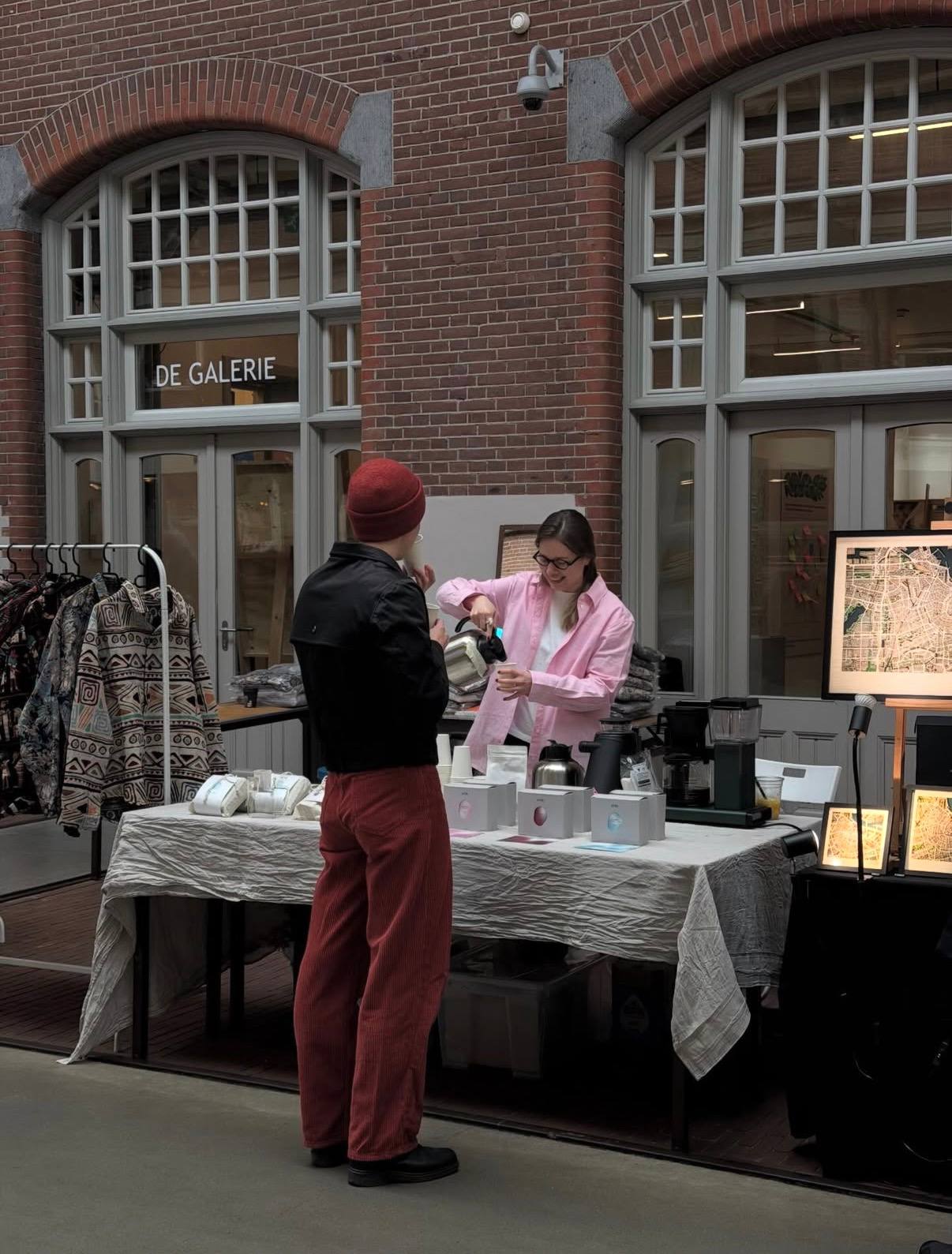 Pouring coffee for a visitor at the ATRI stand in Foodhallen, Amsterdam.